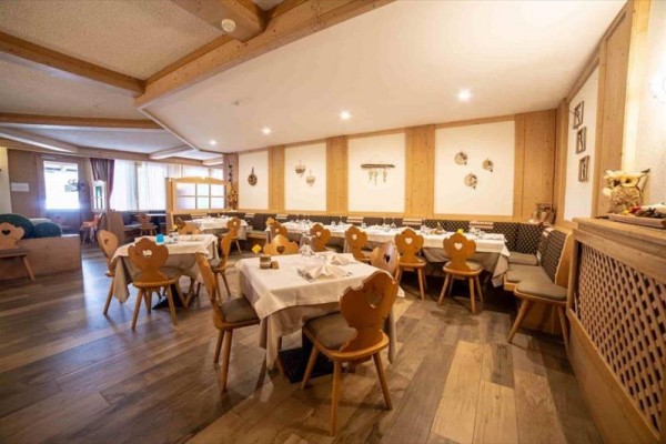 Restauracja z drewnianymi ścianami i stolikami z białymi obrusami.