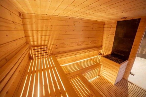 Drewniana sauna z ławkami i piecem.