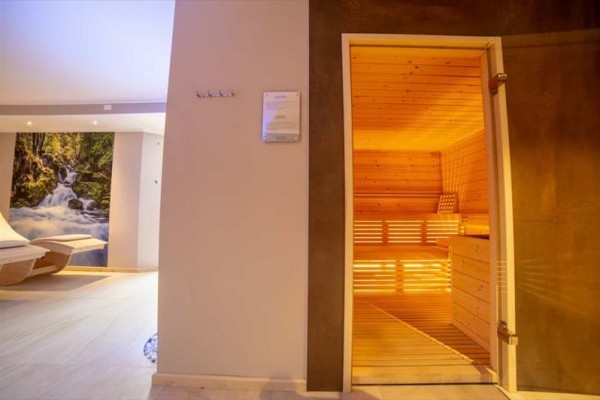 Sauna i pokój relaksacyjny z leżakami i obrazem natury.