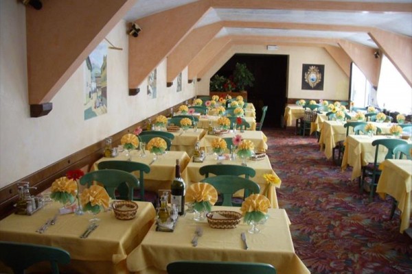 Restauracja z wyprasowanymi obrusami i kwiatowymi dekoracjami na stołach.