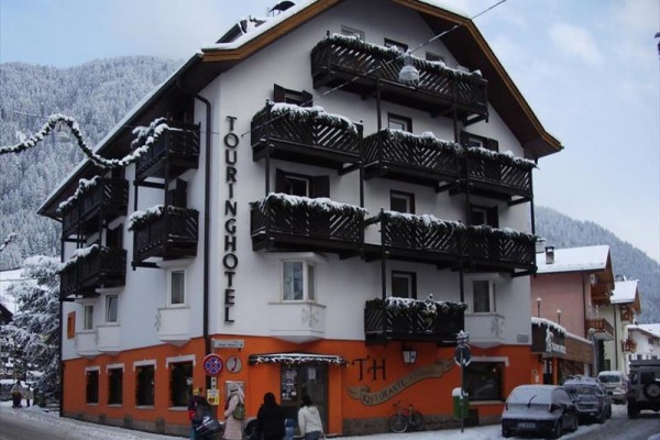 Górski budynek hotelowy z drewnianymi balkonami pokrytymi śniegiem w zimowej scenerii.