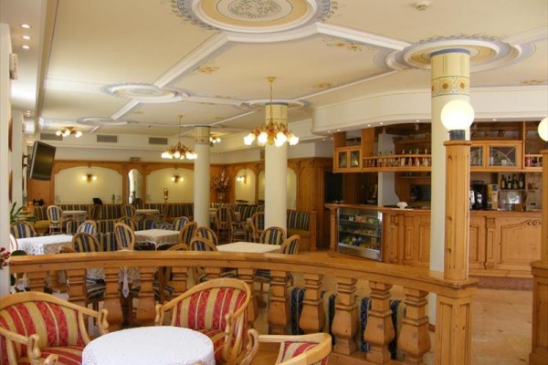 Wnętrze restauracji z drewnianymi meblami i zdobionym sufitem.