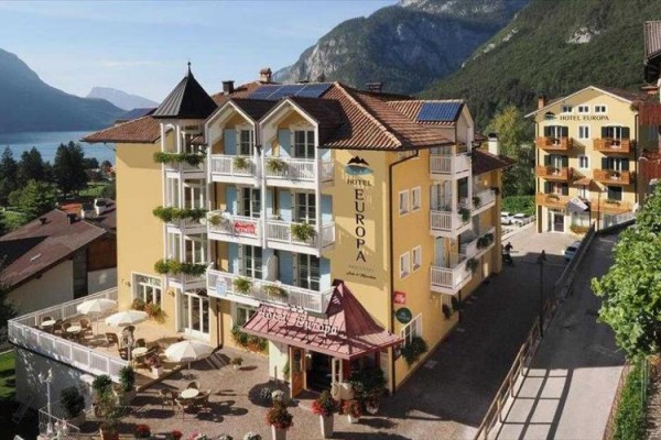 Hotel przy jeziorze z górami w tle.