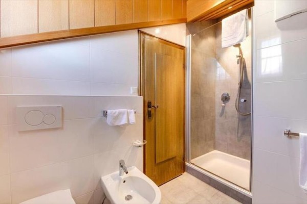 Łazienka z białymi kafelkami, kabiną prysznicową i bidetem.