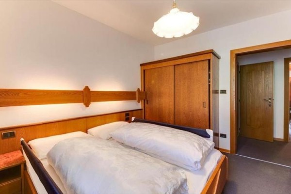 Sypialnia z podwójnym łóżkiem, drewnianą szafą i drzwiami.