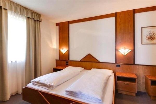 Przestronna sypialnia z podwójnym łóżkiem, drewnianą boazerią i dwiema szafkami nocnymi.