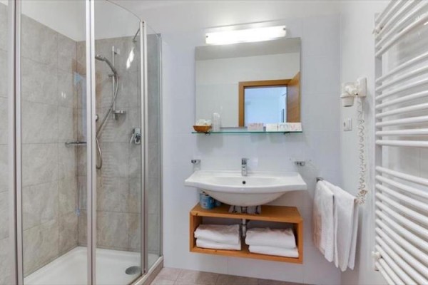 Nowoczesna łazienka z prysznicem, umywalką i lustrem.