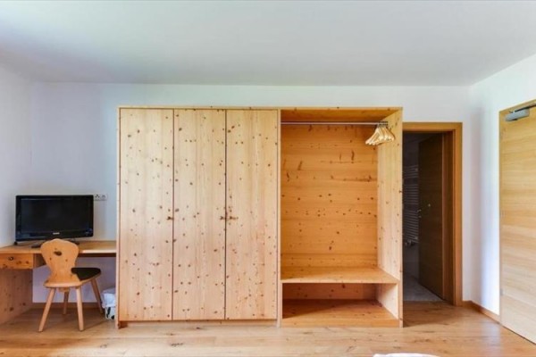 Drewniane meble w pokoju z szafą, biurkiem i telewizorem.