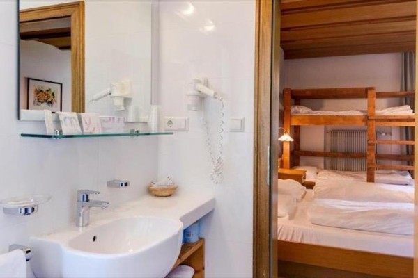 Łazienka z umywalką i lustrem obok pokoju z łóżkiem piętrowym i łóżkiem.