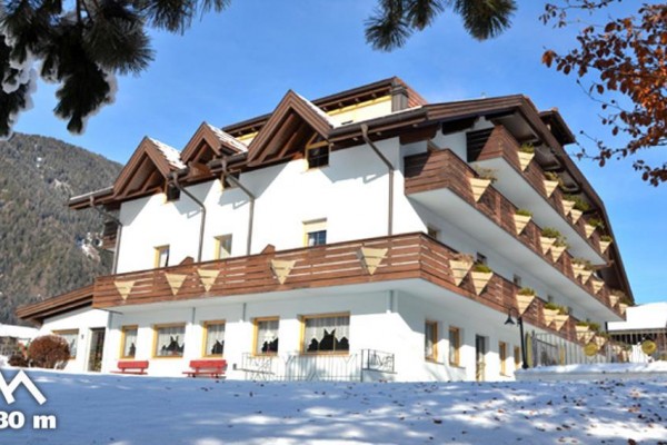 Budynek hotelu otoczony śniegiem z górskim krajobrazem w tle i wysokością 1080 metrów.