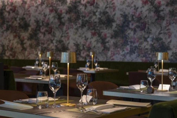 Restauracja z nakrytymi stołami i kwiecistą tapetą.