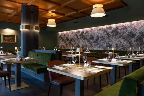 Elegancka restauracja z tapicerowanymi ławkami i obrazami na ścianach.