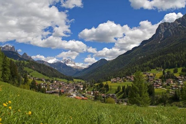 Wioska w dolinie otoczona górami pod niebieskim niebem z chmurami.