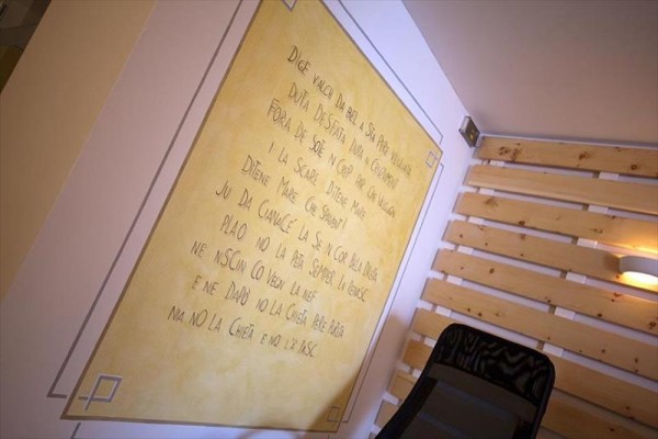 Ściana pokryta drewnianą boazerią i żółtą powierzchnią z napisem w obcym języku.