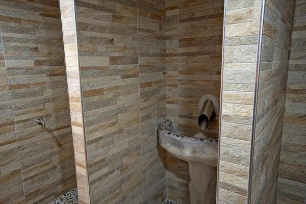 Kamienna umywalka w łazience z ceramicznymi płytkami na ścianach.