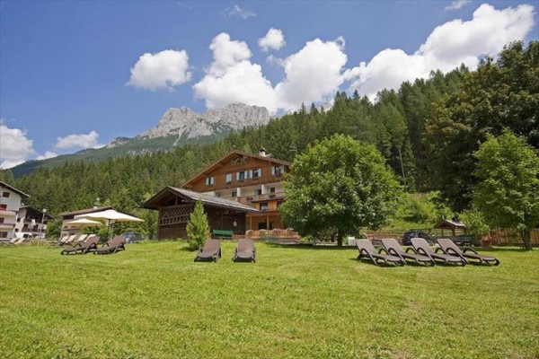 Górski ośrodek otoczony lasami z leżakami na trawniku.