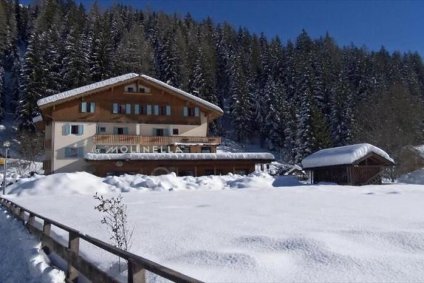 Górska chata otoczona zaśnieżonym lasem w słoneczny zimowy dzień.