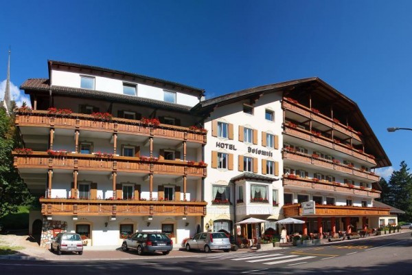 Hotel z drewnianymi balkonami i samochodami zaparkowanymi z przodu.