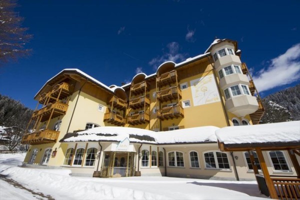 Żółty budynek hotelu pod niebieskim niebem, otoczony śniegiem.