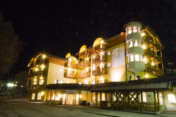 Nocą oświetlony wielopiętrowy hotel z drewnianymi balkonami.