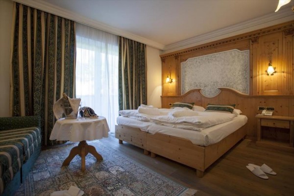 Elegancki pokój hotelowy z łóżkiem małżeńskim i drewnianą boazerią.