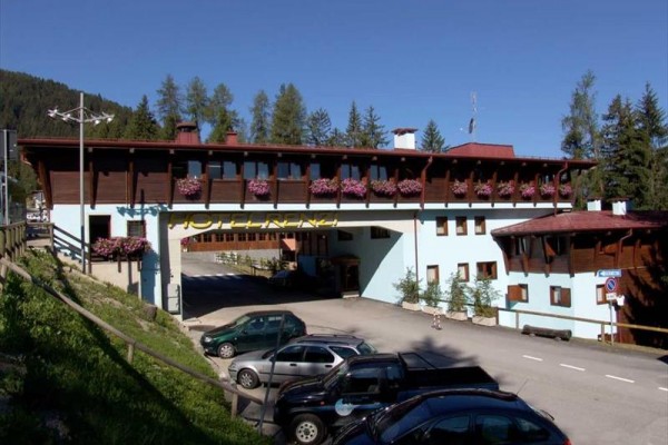 Górski hotel z drewnianymi elementami i kwiatami na balkonach.