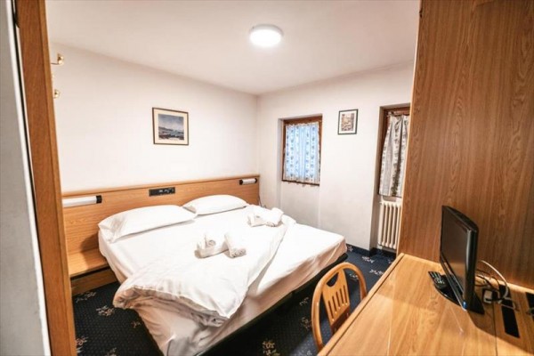 Pokój hotelowy z łóżkiem małżeńskim, stołem i telewizorem na komodzie.