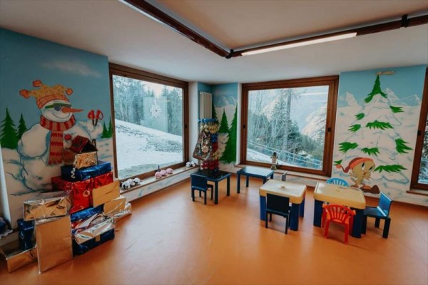 Pokój zabaw dla dzieci z świątecznymi dekoracjami, malowidła bałwana i drzew na ścianach.