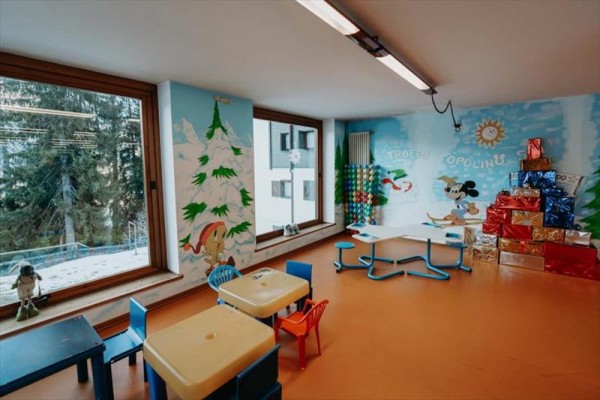 Sala zabaw dla dzieci z kolorowymi meblami i malowidłami na ścianach.