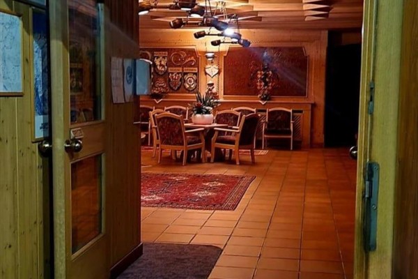 Widok na drewniane wnętrze z jadalnianym stołem i krzesłami, oświetlone ciepłym światłem.