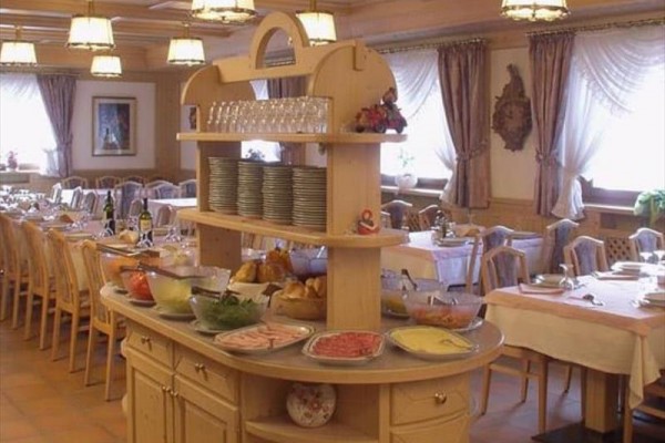 Stół bufetowy z jedzeniem i naczyniami w przestronnej jadalni.