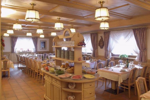 Restauracja z nakrytymi stołami i bufetem z jedzeniem pośrodku.