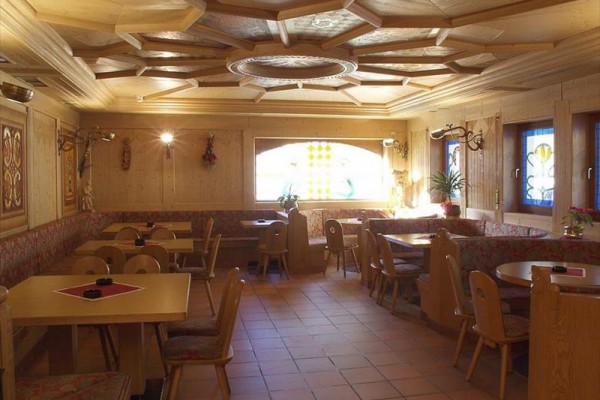 Przytulna restauracja wyłożona drewnem ze stołami i krzesłami.