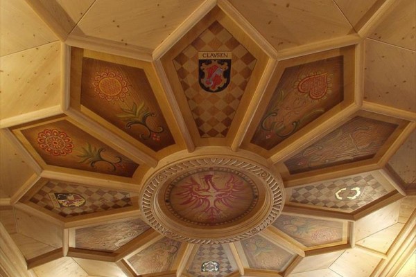 Drewniany sufit z geometrycznym wzorem i ozdobnymi panelami.