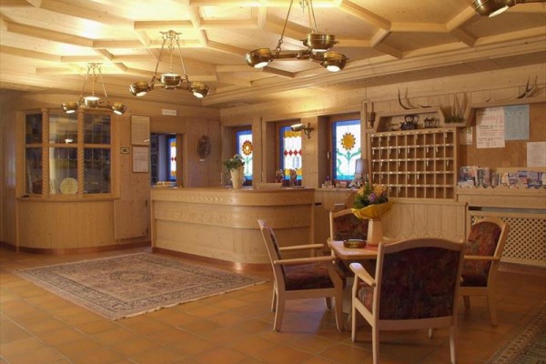 Recepcja z drewnianymi meblami i dekoracjami, witrażowymi oknami i dywanami.