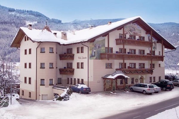 Górski hotel z zaśnieżonym dachem i widokiem na zaśnieżone góry.