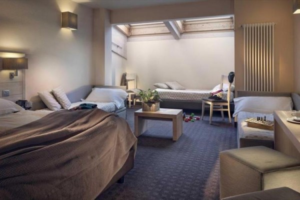 Nowoczesny pokój hotelowy z trzema łóżkami i jasnym wystrojem.