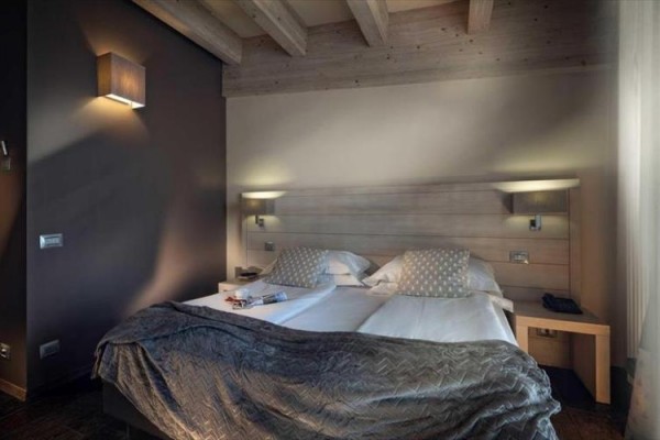 Nowoczesny pokój hotelowy z łóżkiem małżeńskim i drewnianym sufitem.