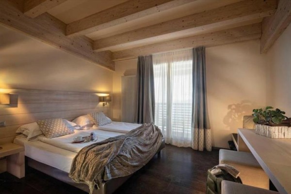 Nowoczesny pokój hotelowy z podwójnym łóżkiem i drewnianym sufitem.