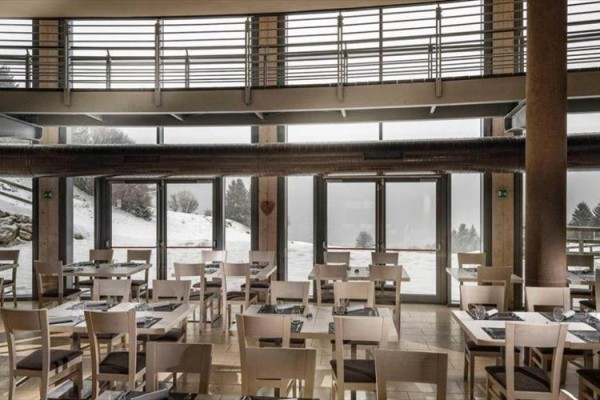 Wnętrze restauracji z widokiem na zaśnieżony krajobraz.