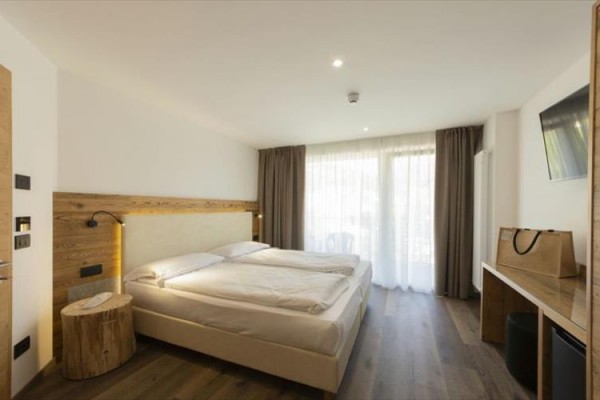 Nowoczesny pokój hotelowy z łóżkiem małżeńskim, biurkiem i dużym oknem.