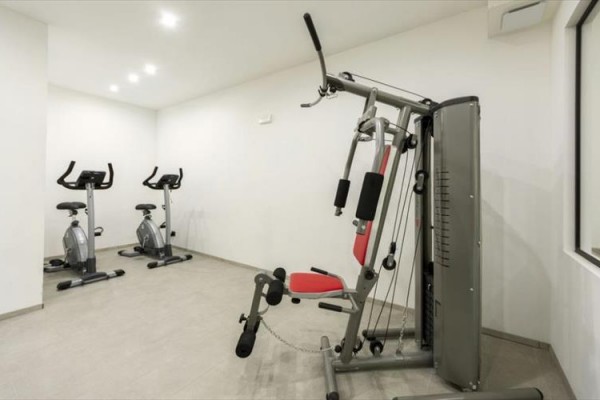 Atlas do ćwiczeń i dwa rowerki stacjonarne w małej siłowni.