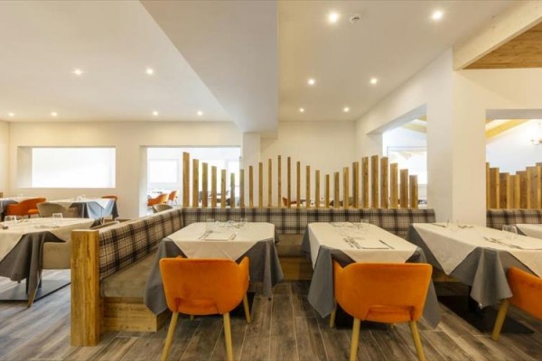 Nowoczesna restauracja z drewnianymi dekoracjami i pomarańczowymi krzesłami.