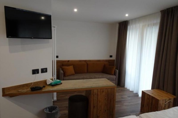 Nowoczesny pokój hotelowy z kanapą, telewizorem na ścianie i drzwiami balkonowymi.