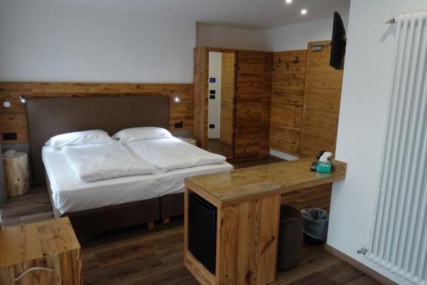 Nowoczesny pokój hotelowy z drewnianymi meblami i podwójnym łóżkiem.