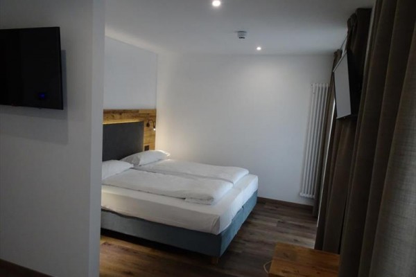 Pokój hotelowy z łóżkiem małżeńskim i nowoczesnym umeblowaniem.