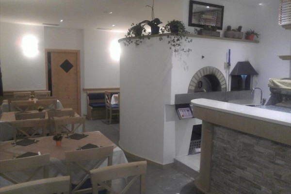 Wnętrze restauracji z drewnianymi stołami i kamiennym piecem.