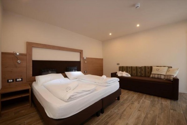 Nowoczesny pokój hotelowy z łóżkiem małżeńskim i sofą.