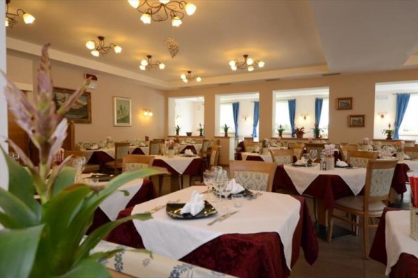 Elegancko nakryta restauracja z białymi obrusami i kwiatowymi dekoracjami.