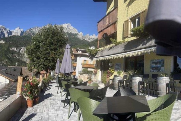 Taras restauracji z widokiem na masyw górski w słoneczny dzień.